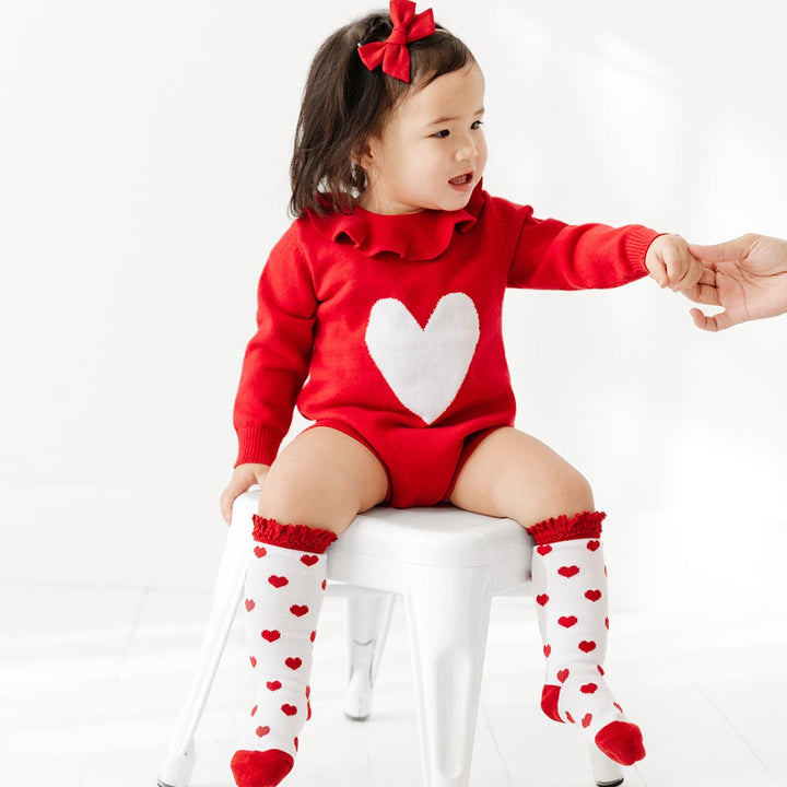 toddler girl wearing valentines heart sweater knit romper with matching knee high socks