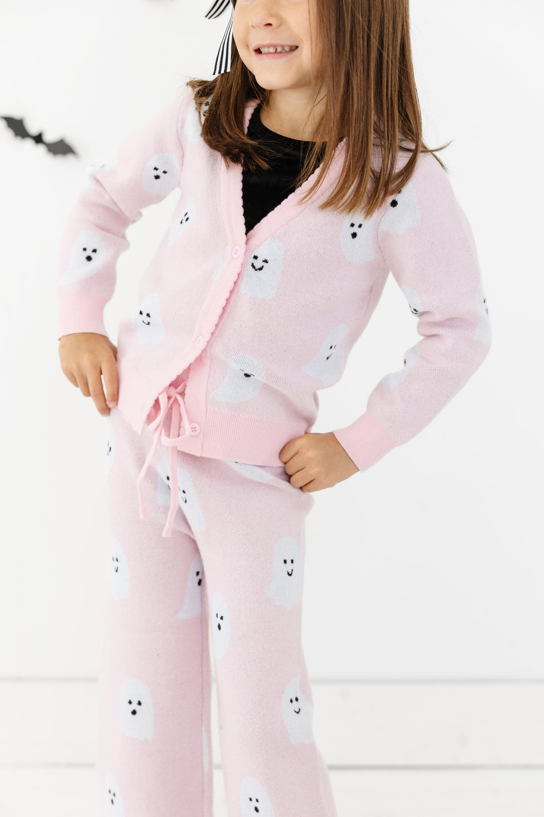 little girl with light pink ghost cardigan buttoned over black velvet top with matching ghost print sweater pants