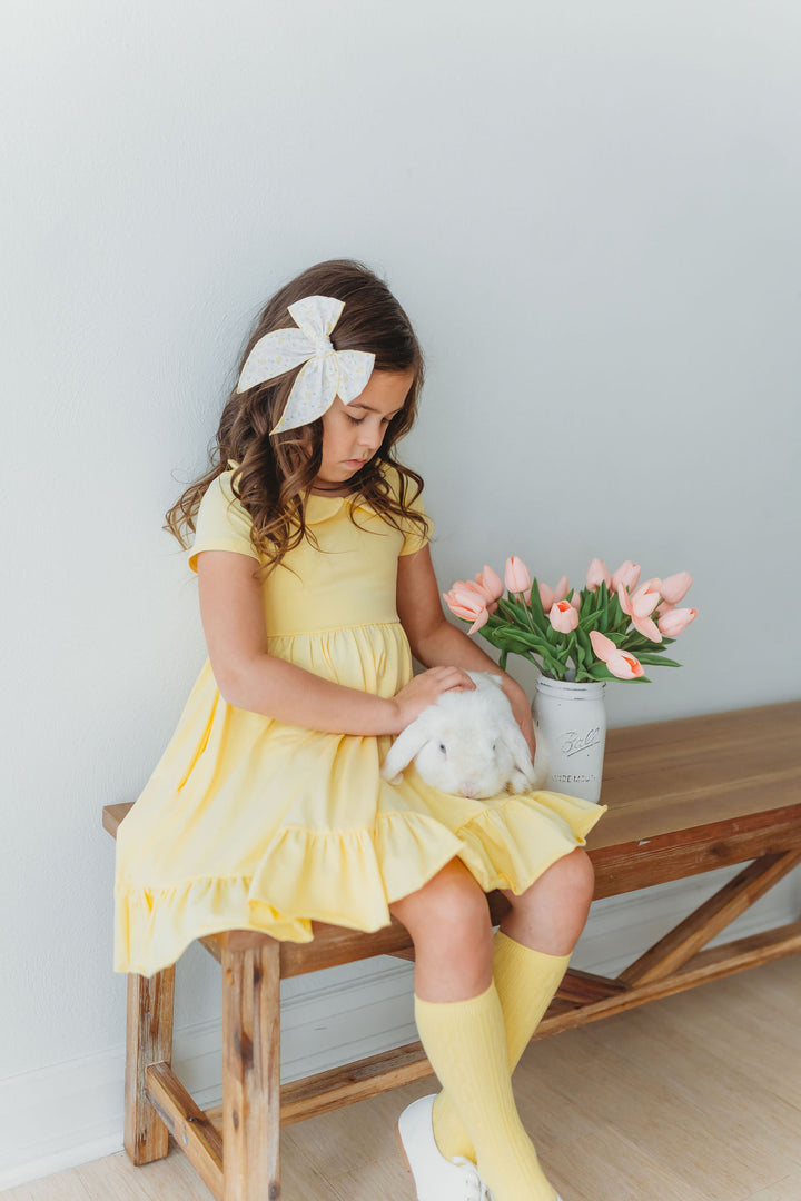 little girl in sunshine yellow cotton dress with bunny on lap