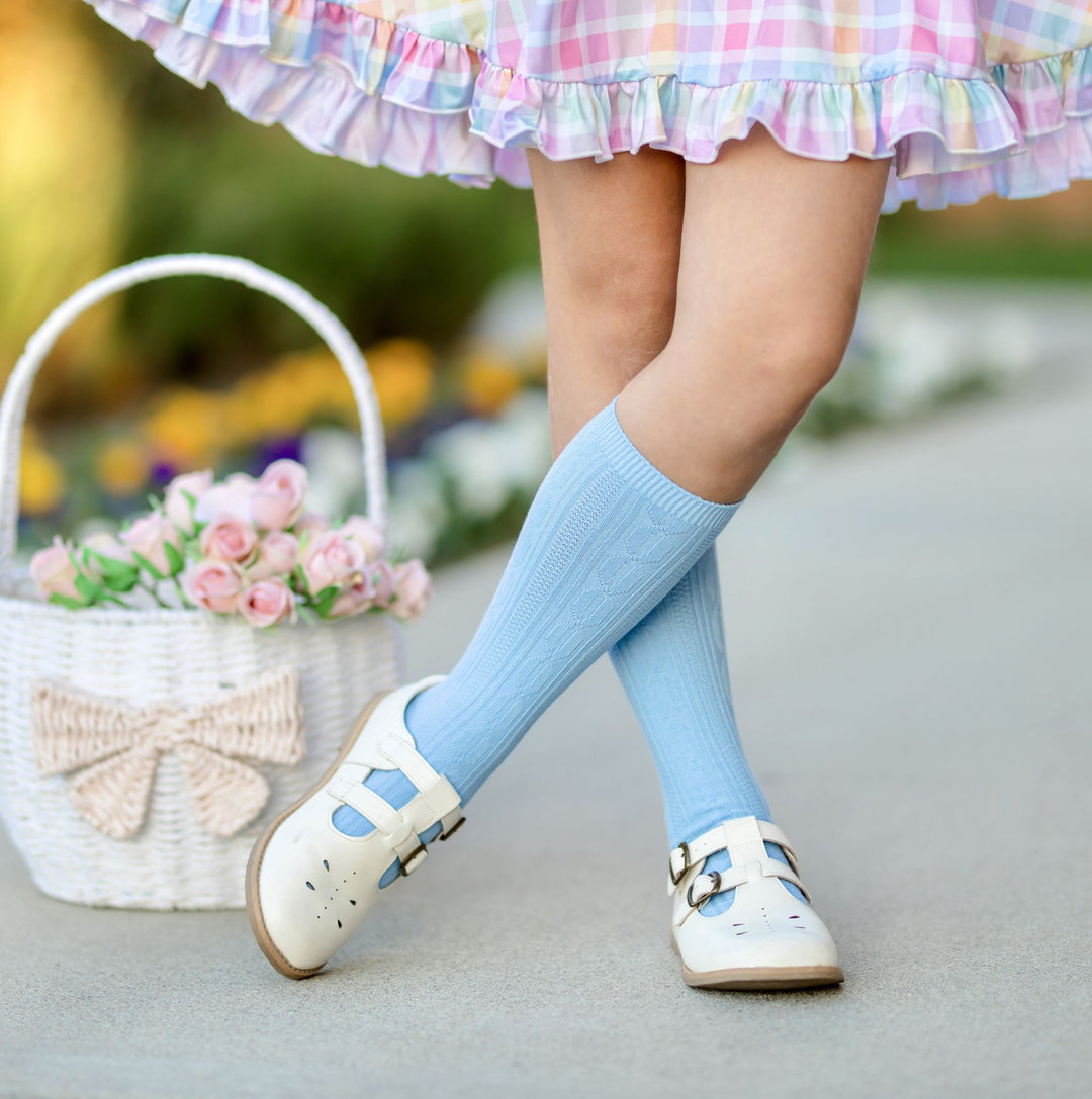 young girl with flower filled Easter basket wearing spring blue cable knit knee socks and pastel gingham twirl dress