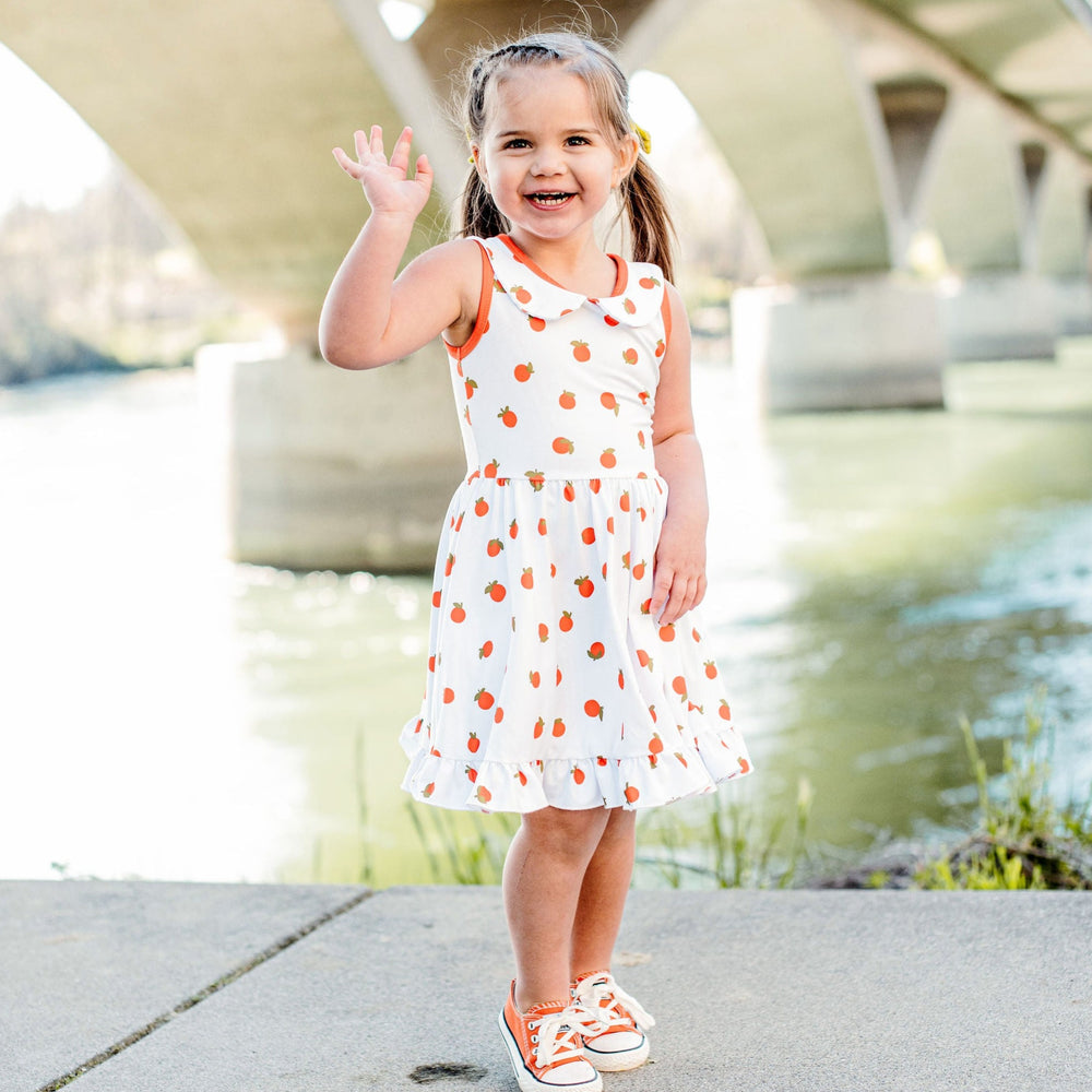 little girl wearing summer twirl dress with oranges print