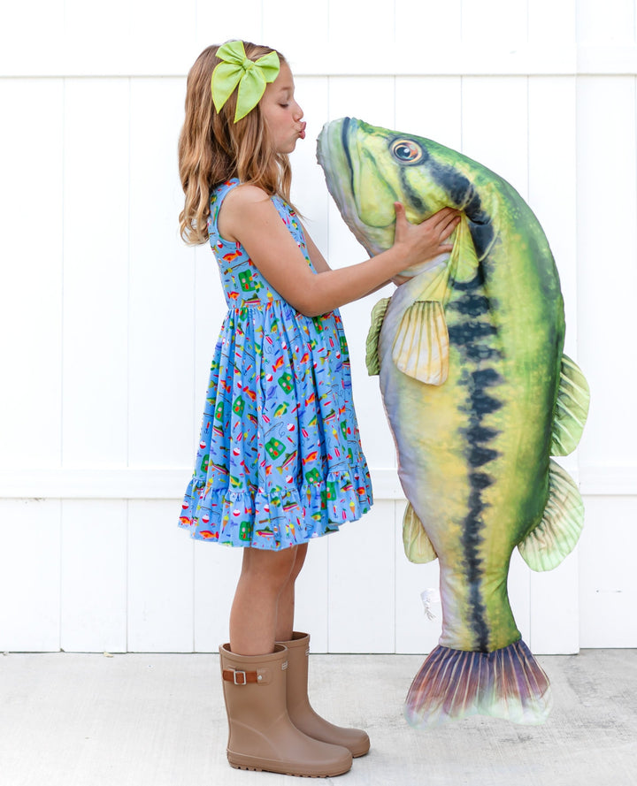 little girl holding giant fish stuffy wearing fishing themed dress and making fishy face
