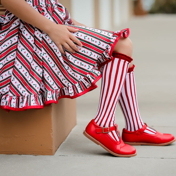 girls candy cane stripe knee high socks paired with christmas wallpaper twirl dress