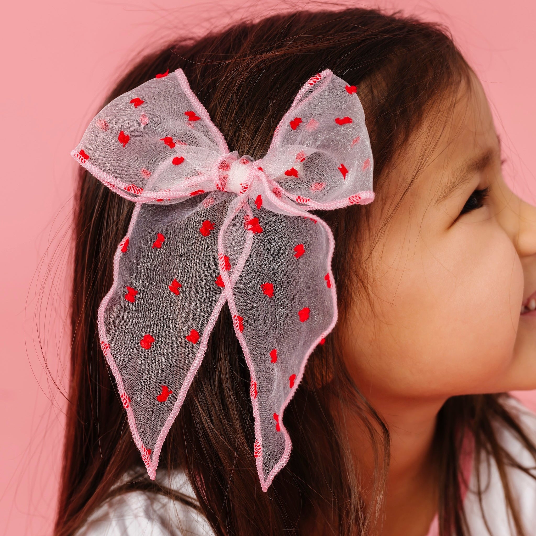 little girl in light pink sheer hair bow with red dots to match Valentine's collection