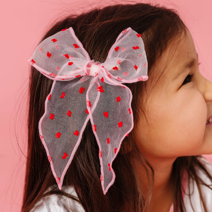 little girl in light pink sheer hair bow with red dots to match Valentine's collection