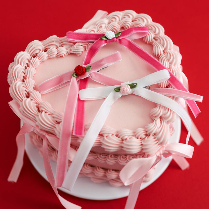 three velvet ribbon hair bows in shades of pink and white with rosette embellishments in the center