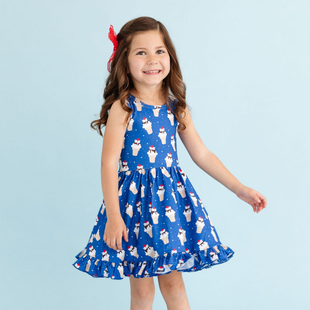 little girl in bright blue ice cone print twirl dress with matching red hair bow