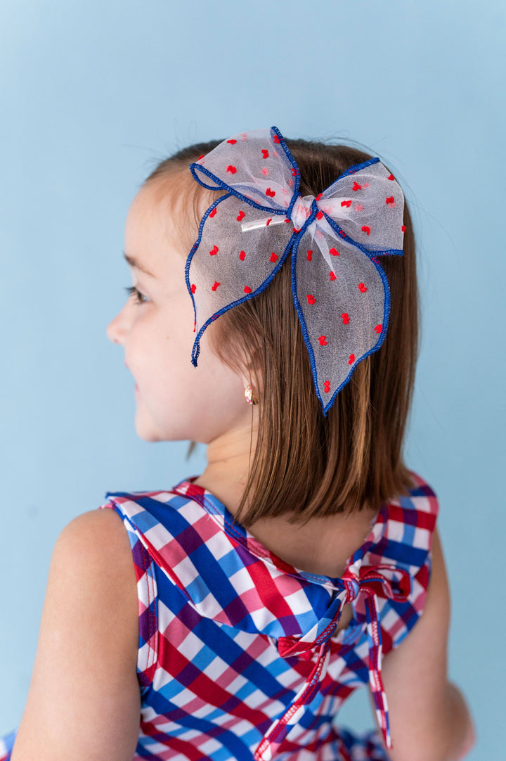 little girl in red, white and blue gingham twirl with matching sheer dot hair bow