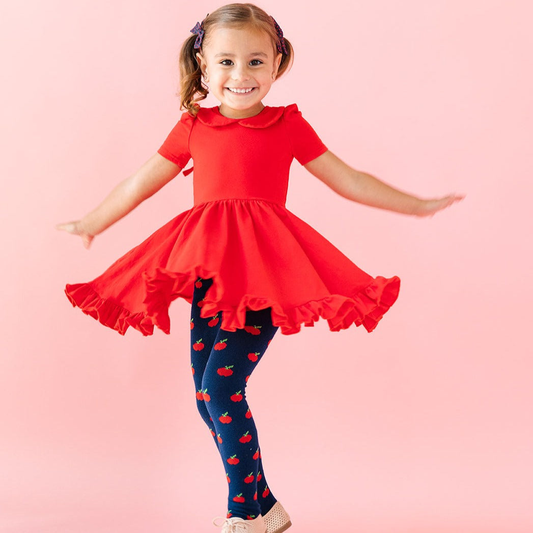 little girl wearing apple patterned tights with red twirl dress for back to school