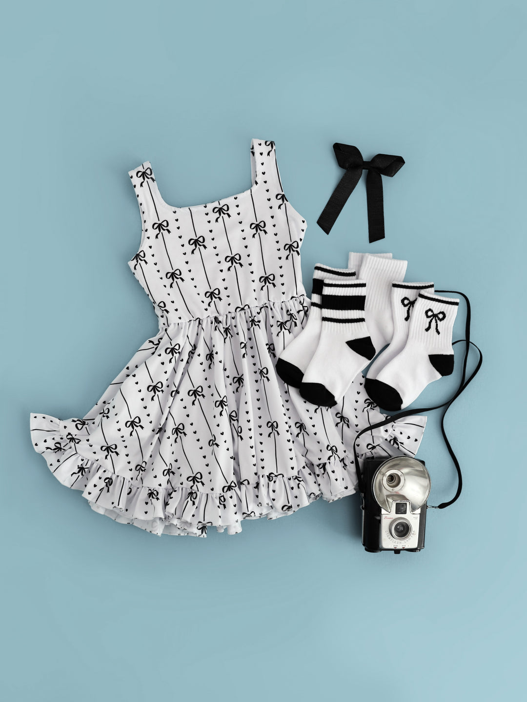 girls monochrome outfit inspired by Audrey Hepburn featuring white tank twirl with ribbon and heart print paired with matching black and white crew sock bundle and black ribbon hair bow