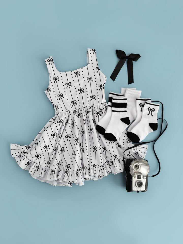 girls monochrome outfit inspired by Audrey Hepburn featuring white tank twirl with ribbon and heart print paired with matching black and white crew sock bundle and black ribbon hair bow