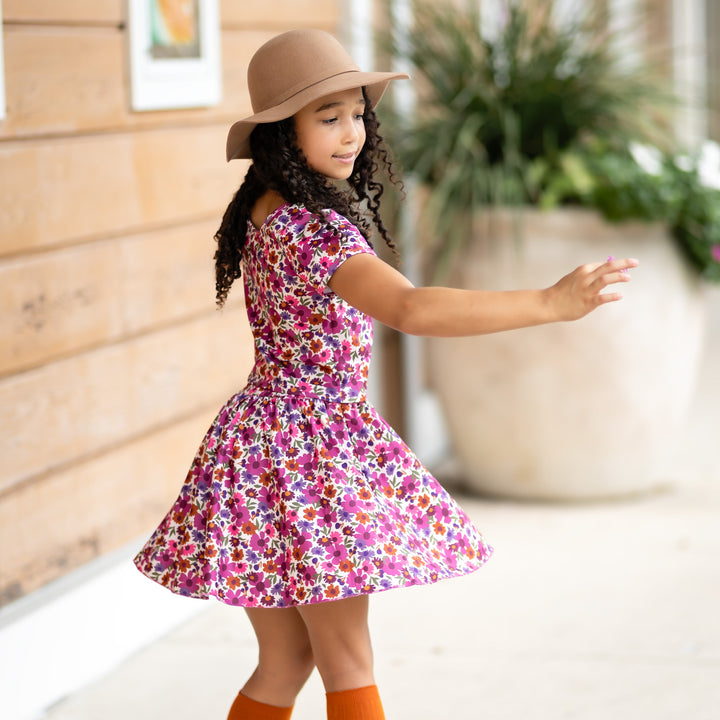 girl twirling in fall floral fitted top and matching skort paired with pumpkin spice knee highs and fall hat