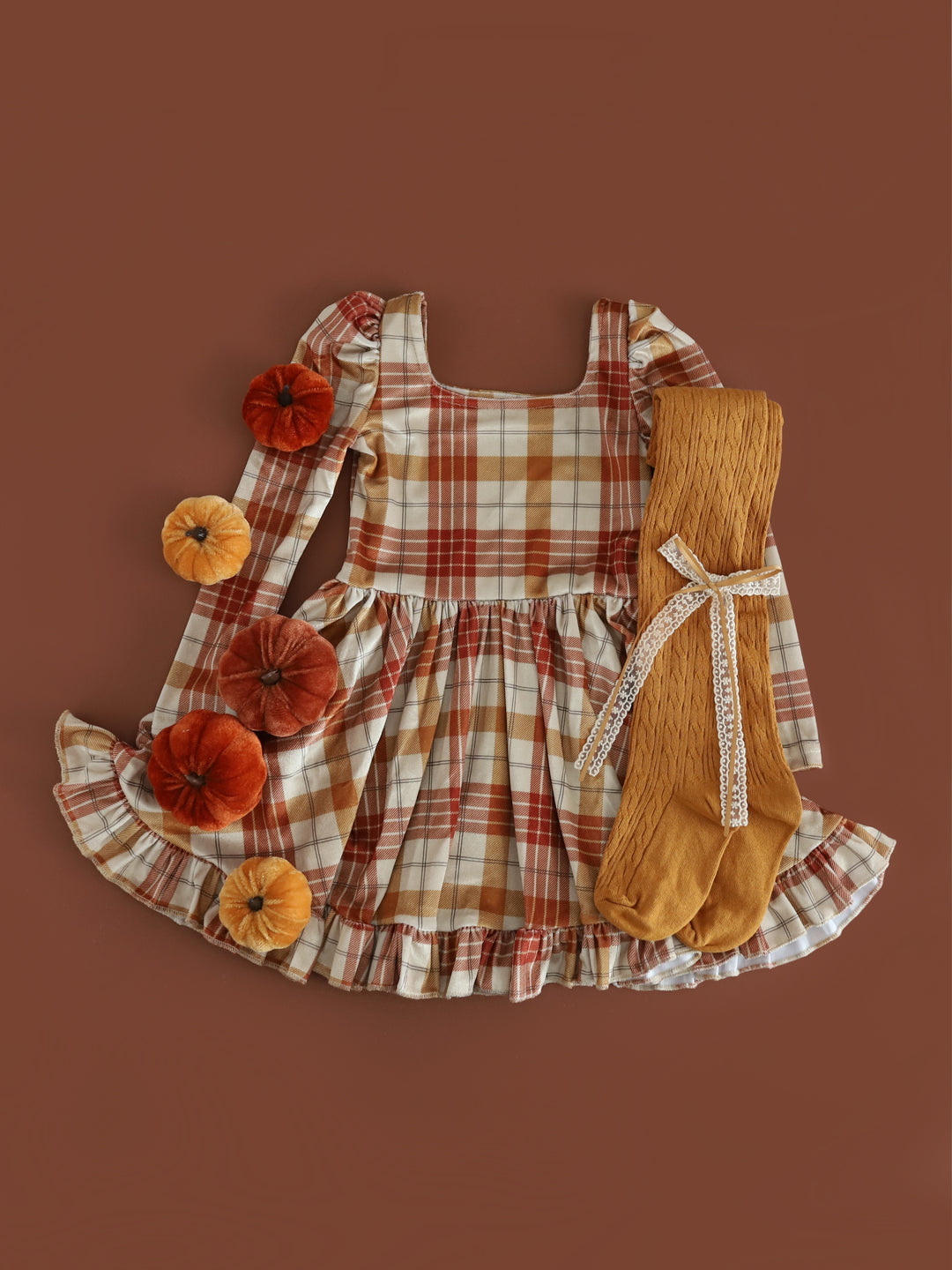 styled fall flatlay photo for girl's velvet long sleeve twirl dress with cream base and burnt orange and mustard plaid paired with mustard cable knit tights and matching lace bow