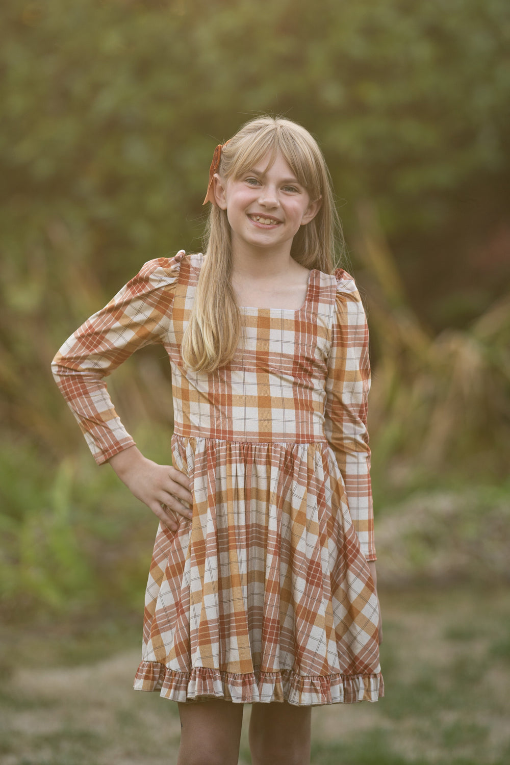 girl in long sleeve velvet twirl dress with cream base and pumpkin and mustard plaid print