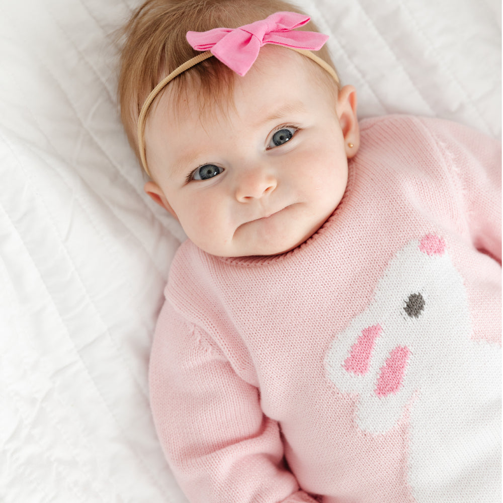 baby in a knit pink romper with white bunny on it