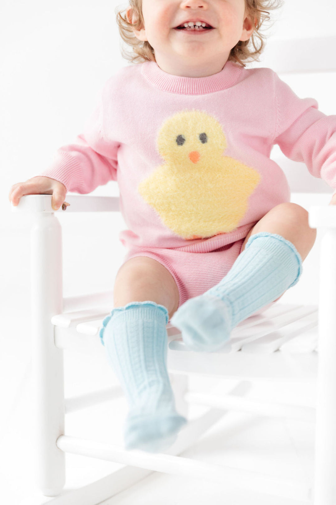 baby girl sitting in pink knit sweater and bloomer set with fuzzy chick detail paired with blue scalloped knee highs