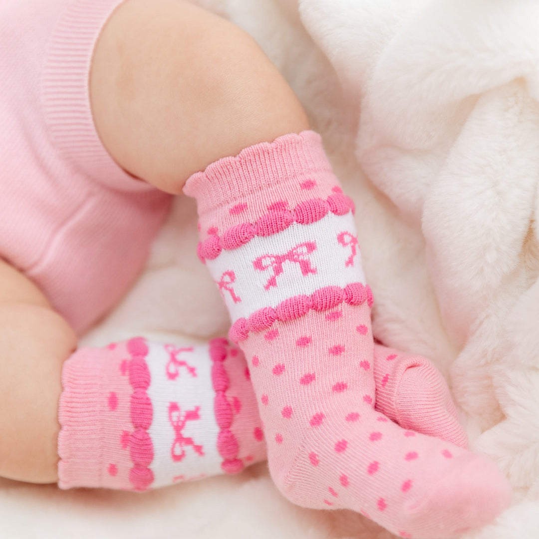 pink scalloped knee highs with polka dots and printed bows on baby girl legs