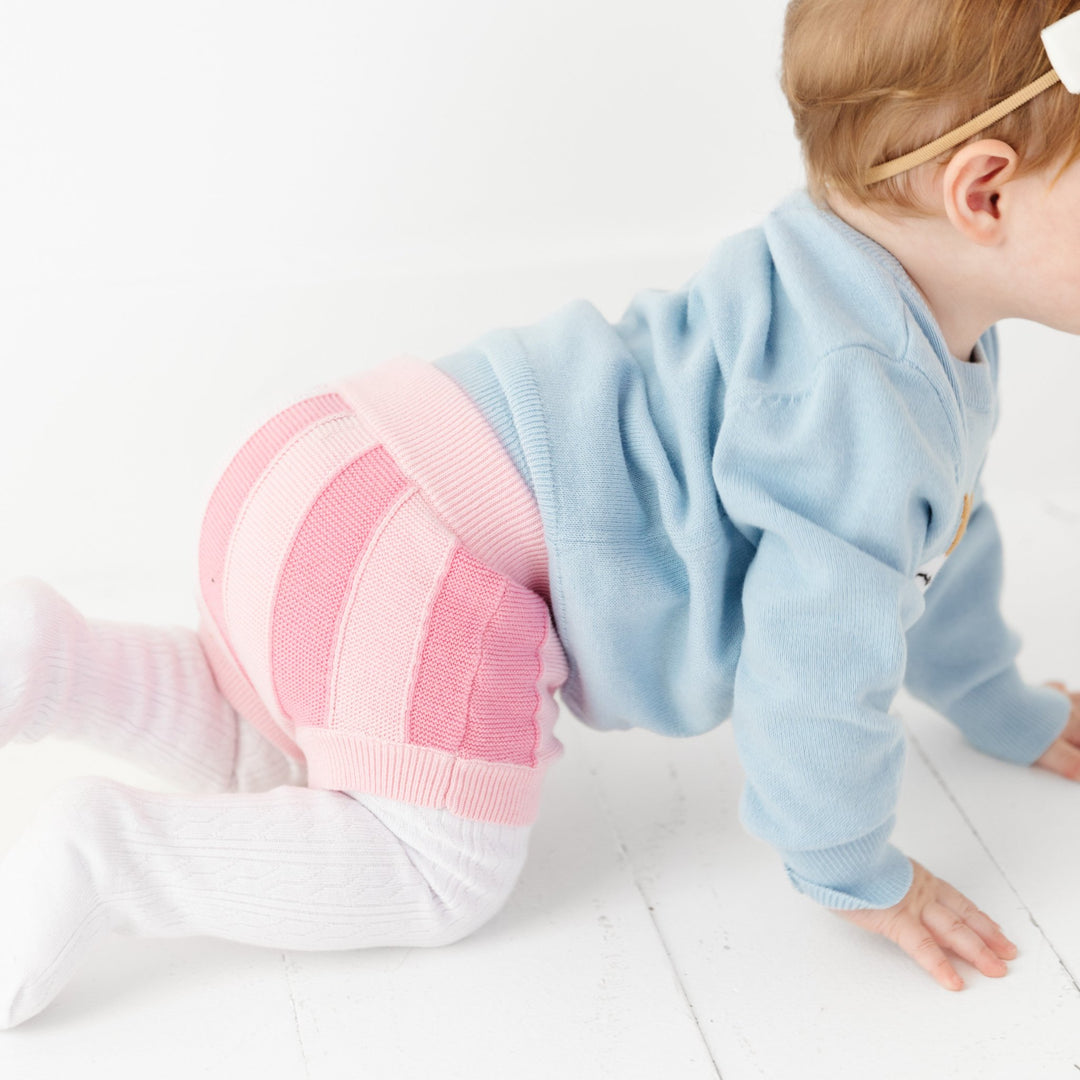 baby girl wearing pink striped sweater bloomers with matching knit sweater and tights