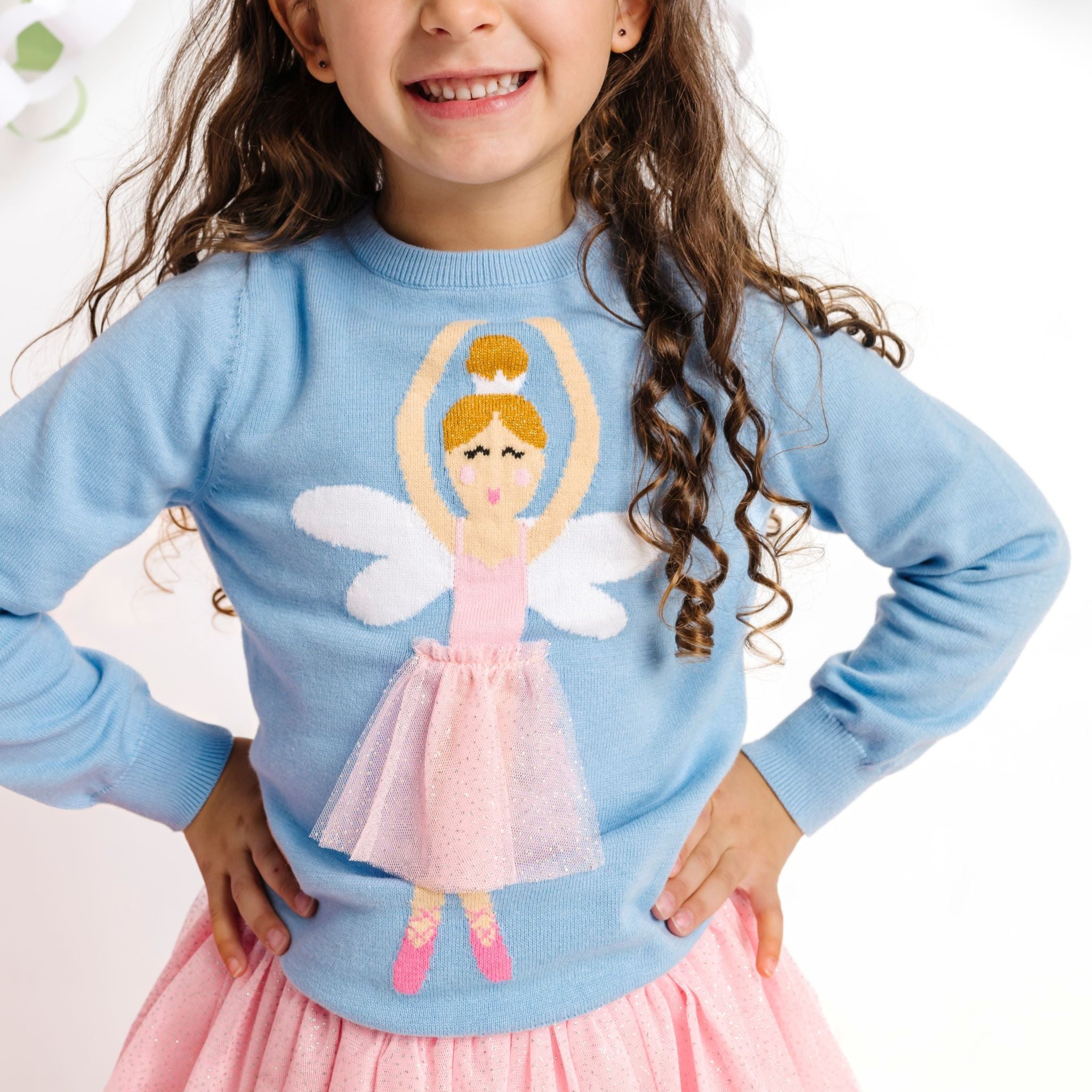 closeup of little girl in sparkle tutu and blue cotton knit sweater with winged ballerina wearing a matching sparkly tutu