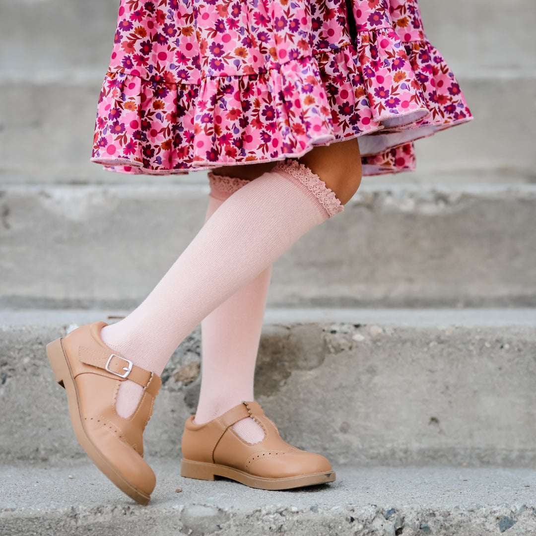 girl wearing blush pink lace top knee highs and floral dress