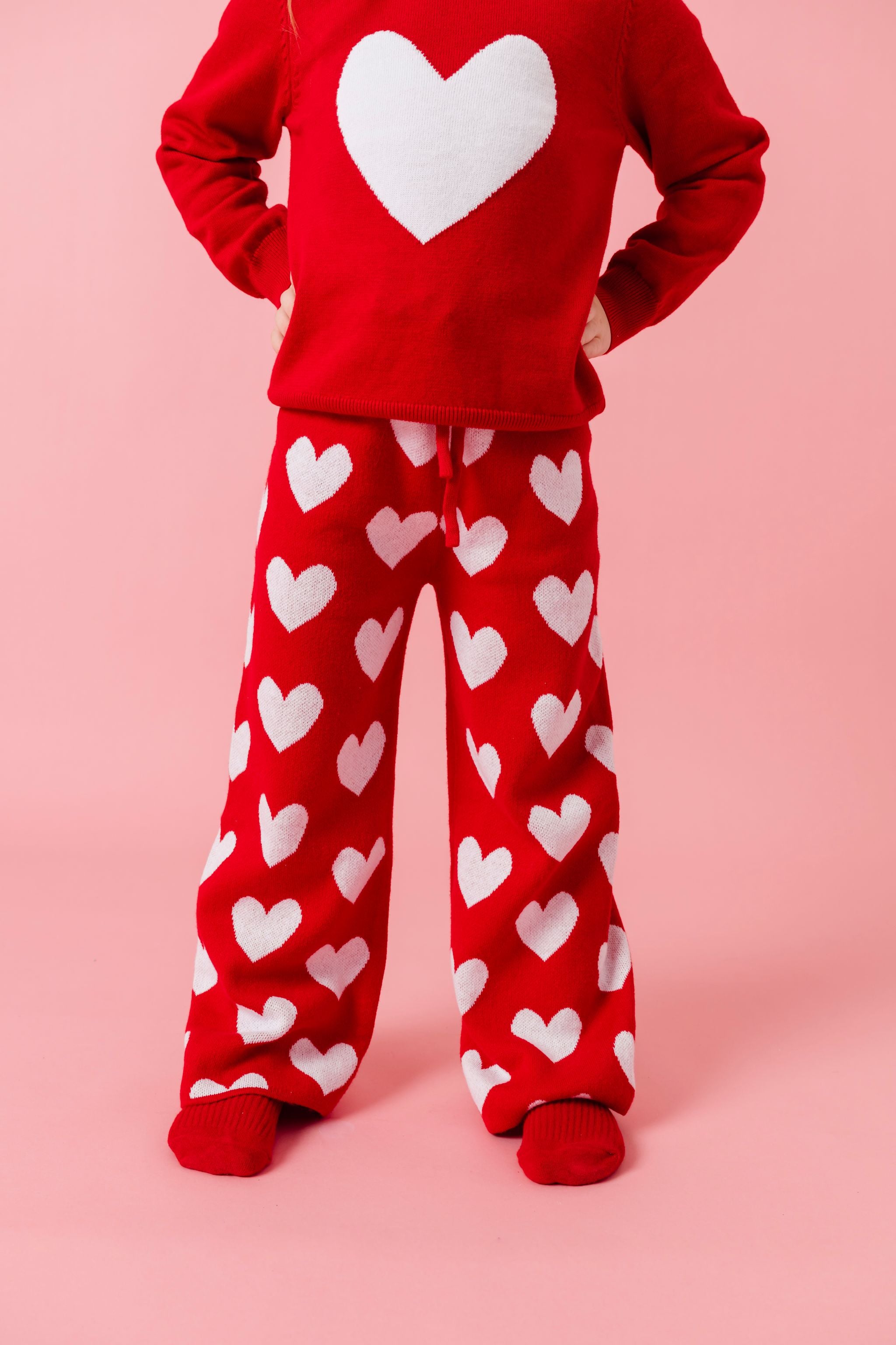 child in bright red sweater with large white heart design and matching red sweater pants with all over white heart design for valentine's day