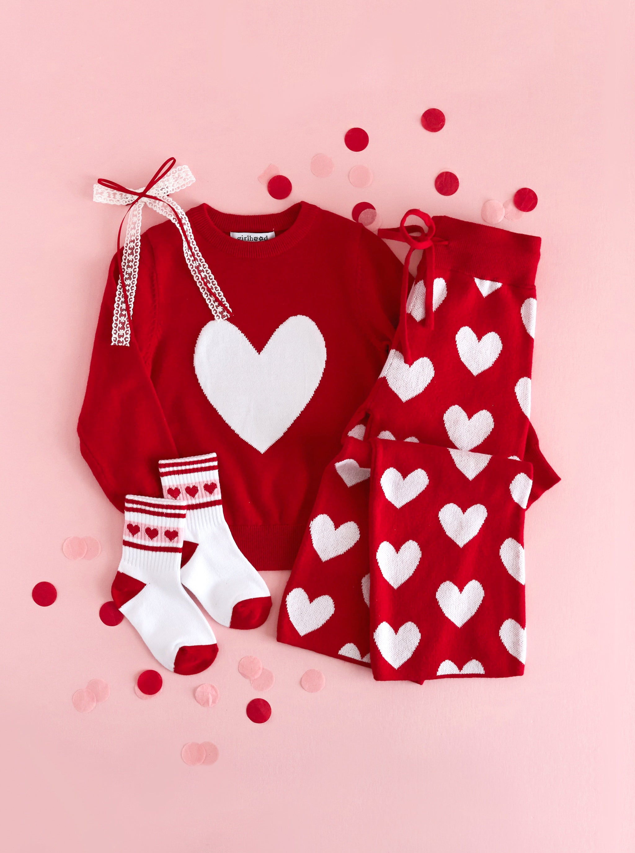 girls red sweater and matching red sweater pant set with white heart design paired with matching valentines themed crew socks and red and white lace hair bow