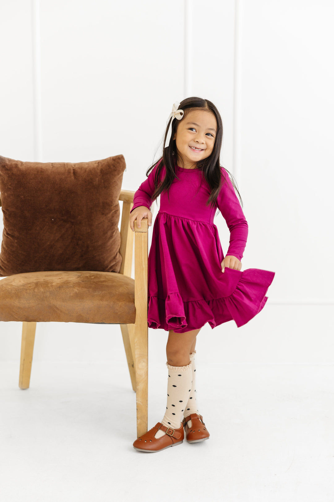 little girl in raspberry cotton knit twirl dress with long sleeves, vanilla lace top knee highs with black polka dots and cream satin bow for fall photos