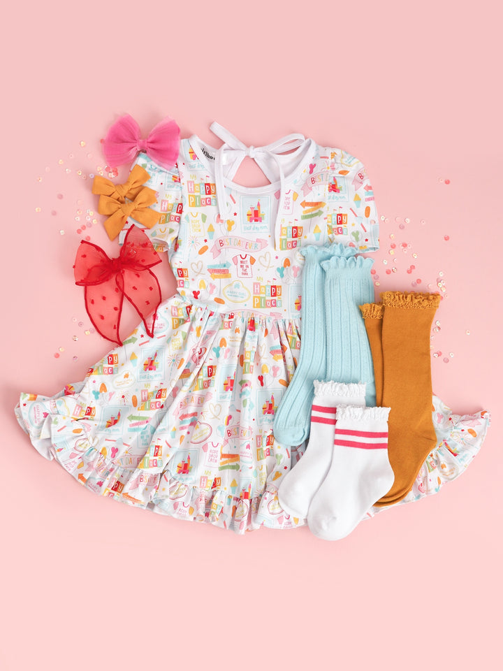 flatlay of girls disney inspired best day ever twirl dress with matching blue and yellow socks and red, yellow, and pink bows