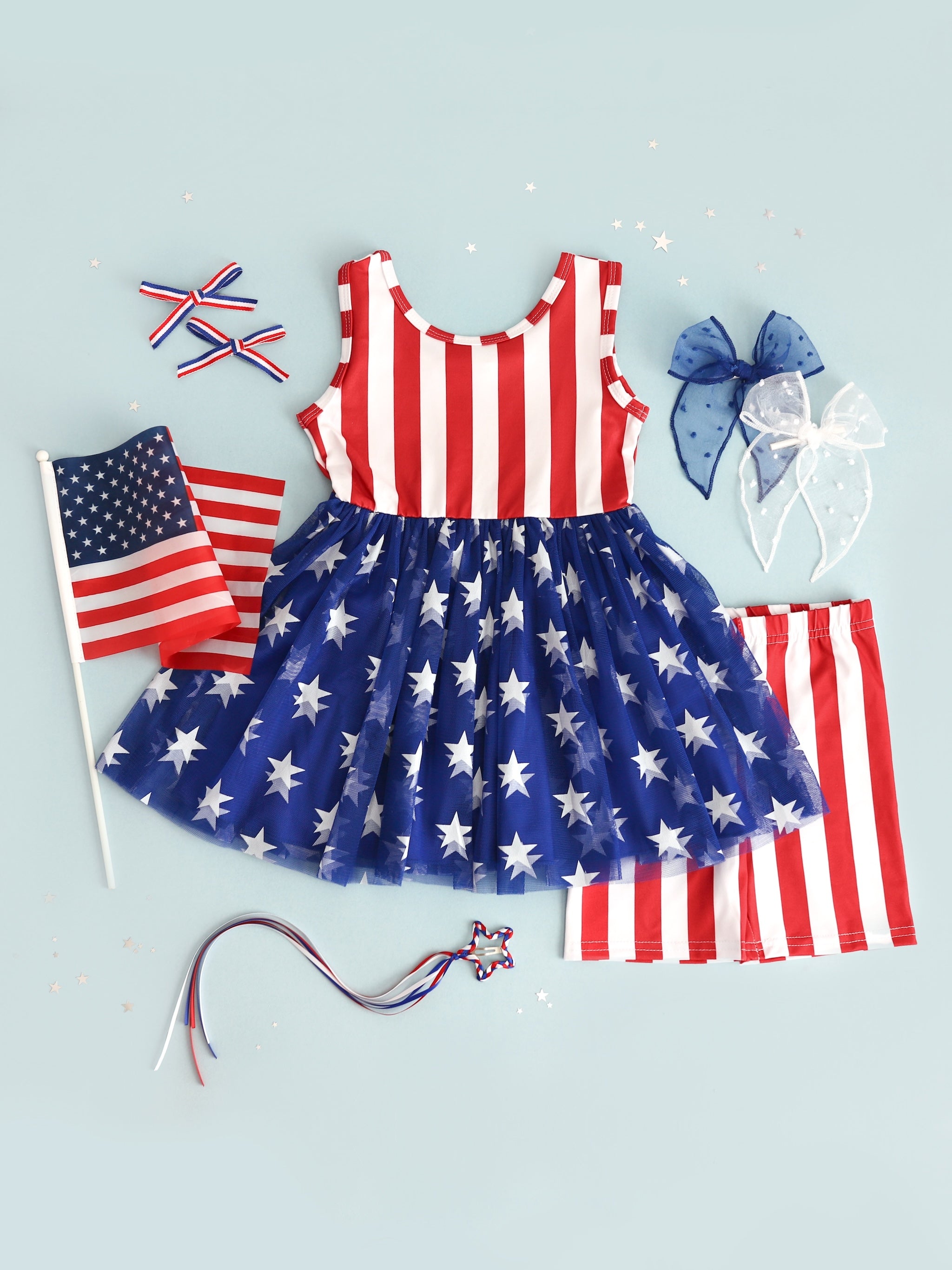 flatlay of girls 4th of july stars and stripes tutu set with matching striped shorts with matching hairbows
