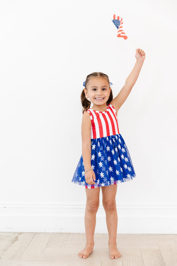 girl wearing 4th of july tutu set with matching shorts and waving flag