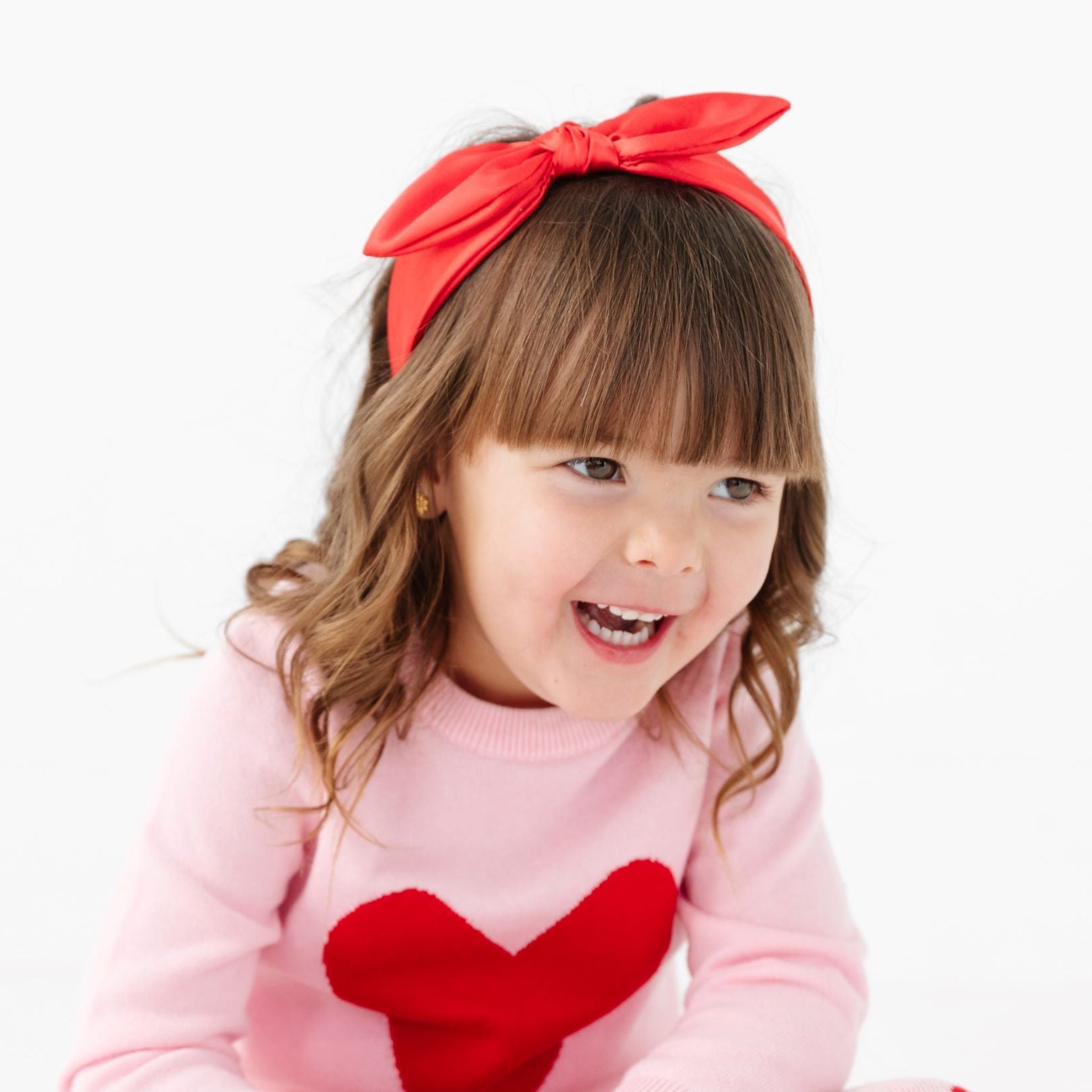 little girl in red satin bow headband and matching Valentine's heart sweater