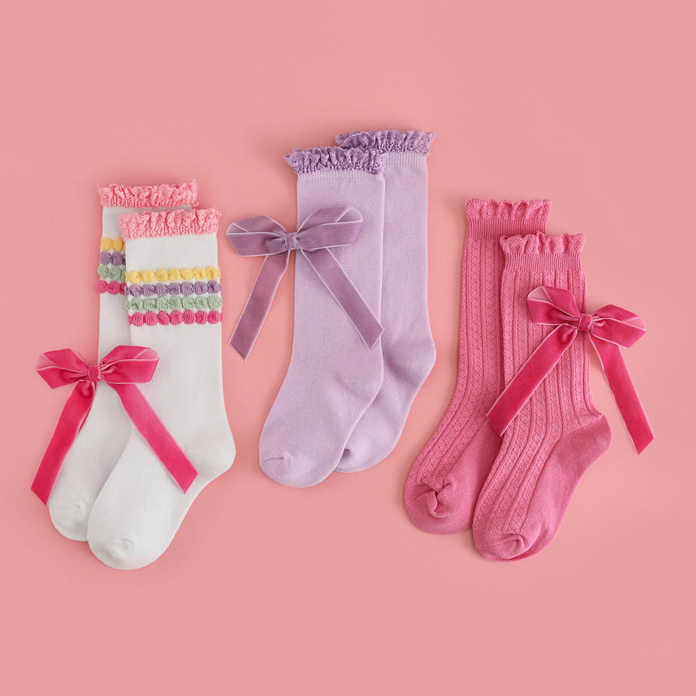three pairs of little girls' pastel knee high socks with matching velvet ribbon bows to pair with birthday themed dress bundles