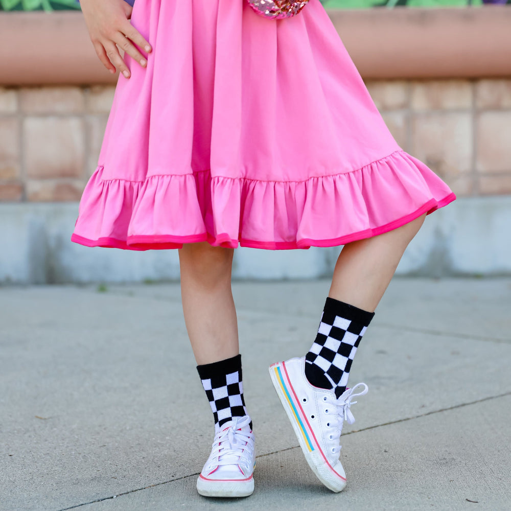 girl posing in pink twirl dress wearing black and white checkered midi socks
