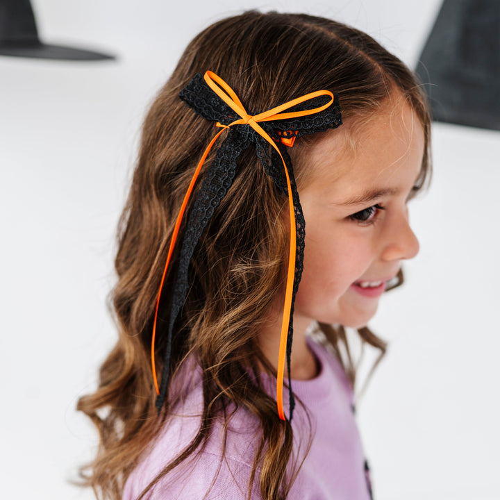 little girl in long black lace hair bow with orange ribbon accent bow on clip paired with lavender kitten sweater for HAlloween