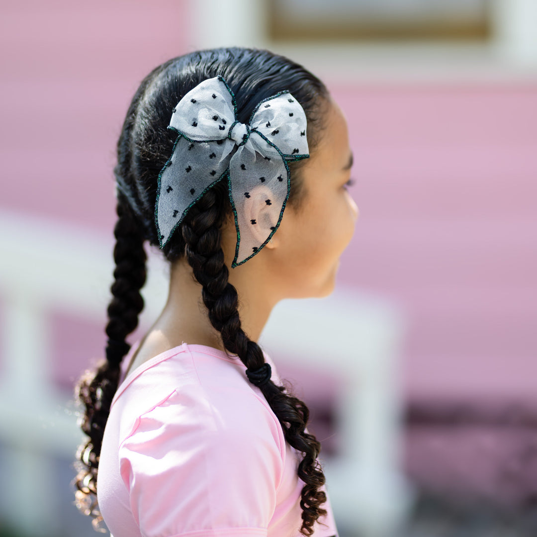 girl in braids with sheer white with black dot and sparkly black trim Halloween bow on clip