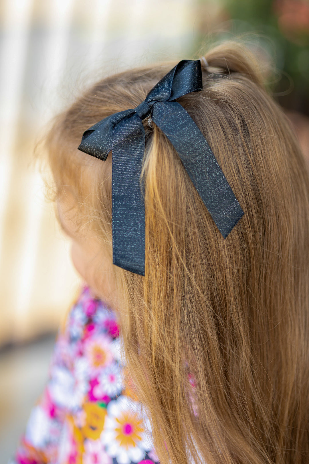 little girl wearing shimmery black ribbon bow on clip paired with halloween themed floral velvet twirl dress
