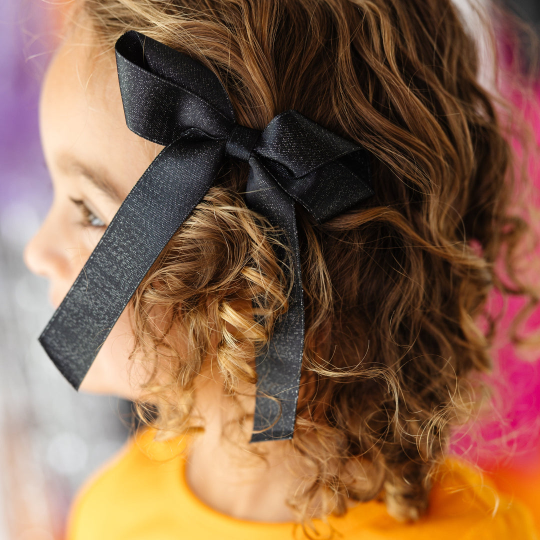 little girl in black shimmery ribbon bow on clip for Halloween