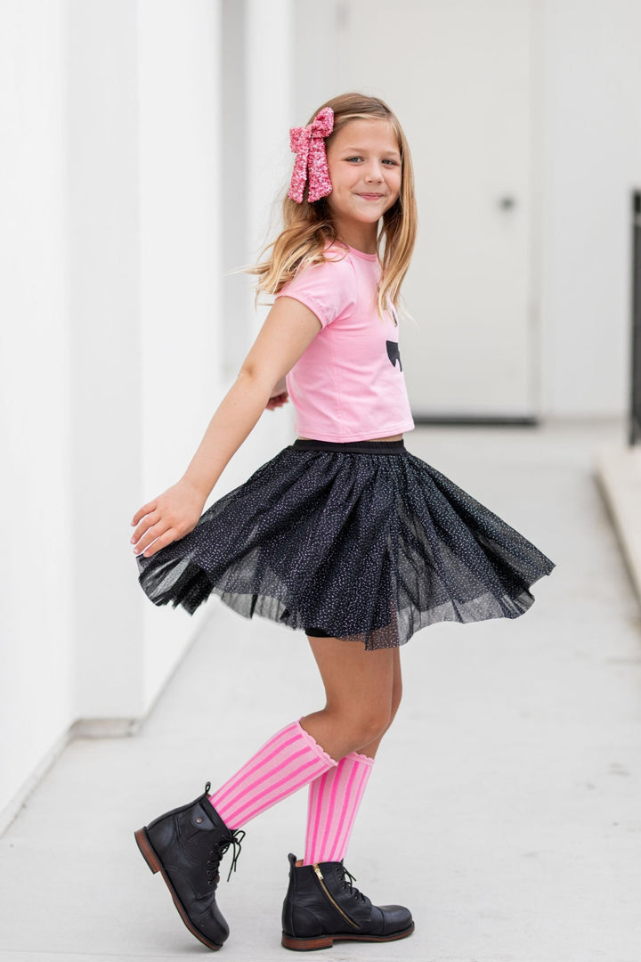 little girl twirling in sparkly black tulle skort with attached shorts and pink knee socks, top and sequin bow for pink Halloween
