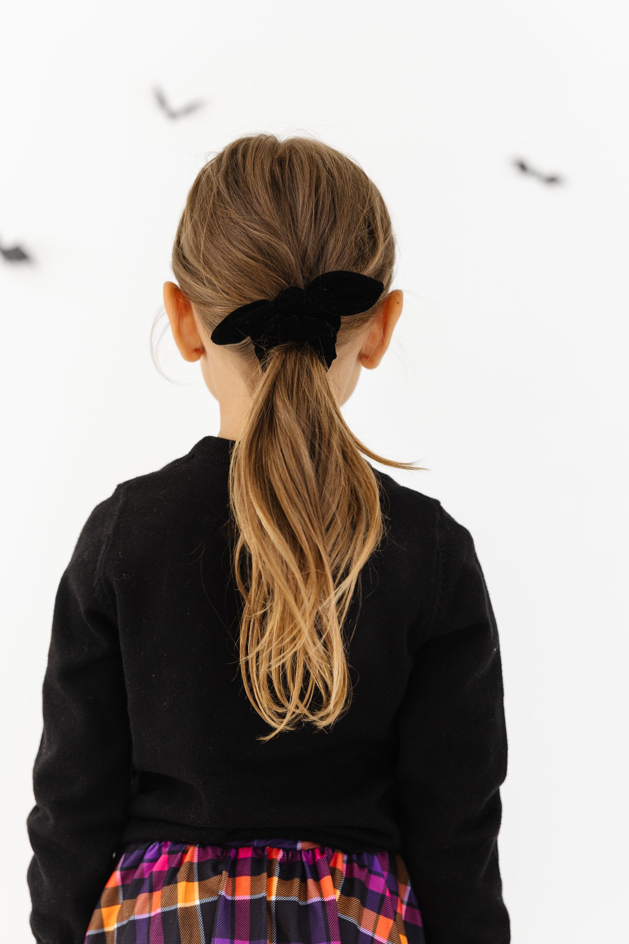 girl in ponytail with black velvet bow scrunchie to match Halloween outfits