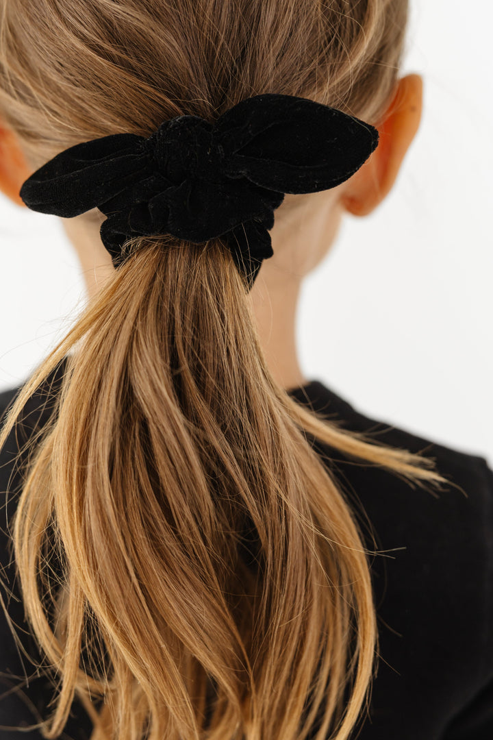 closeup of girls' black velvet scunchie with bow knot detail