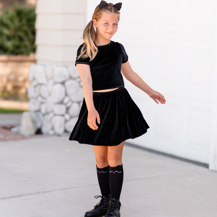 little girl in black cat ears and knee highs and black velvet fitted top with  matching skort for Halloween