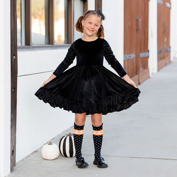 girl wearing black velvet dress with halloween knee high socks