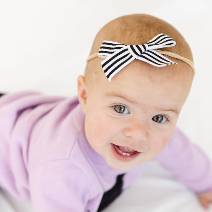 baby girl in lavender sweater and black and white striped ribbon bow on nylon headband for Halloween