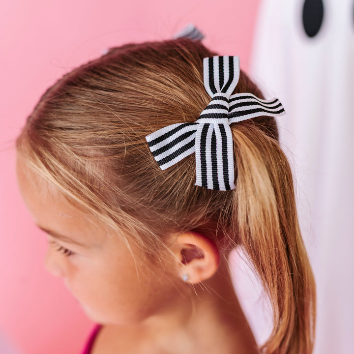 little girl with black and white striped ribbon pigtails bows on clips paired with hot pink velvet twirl dress