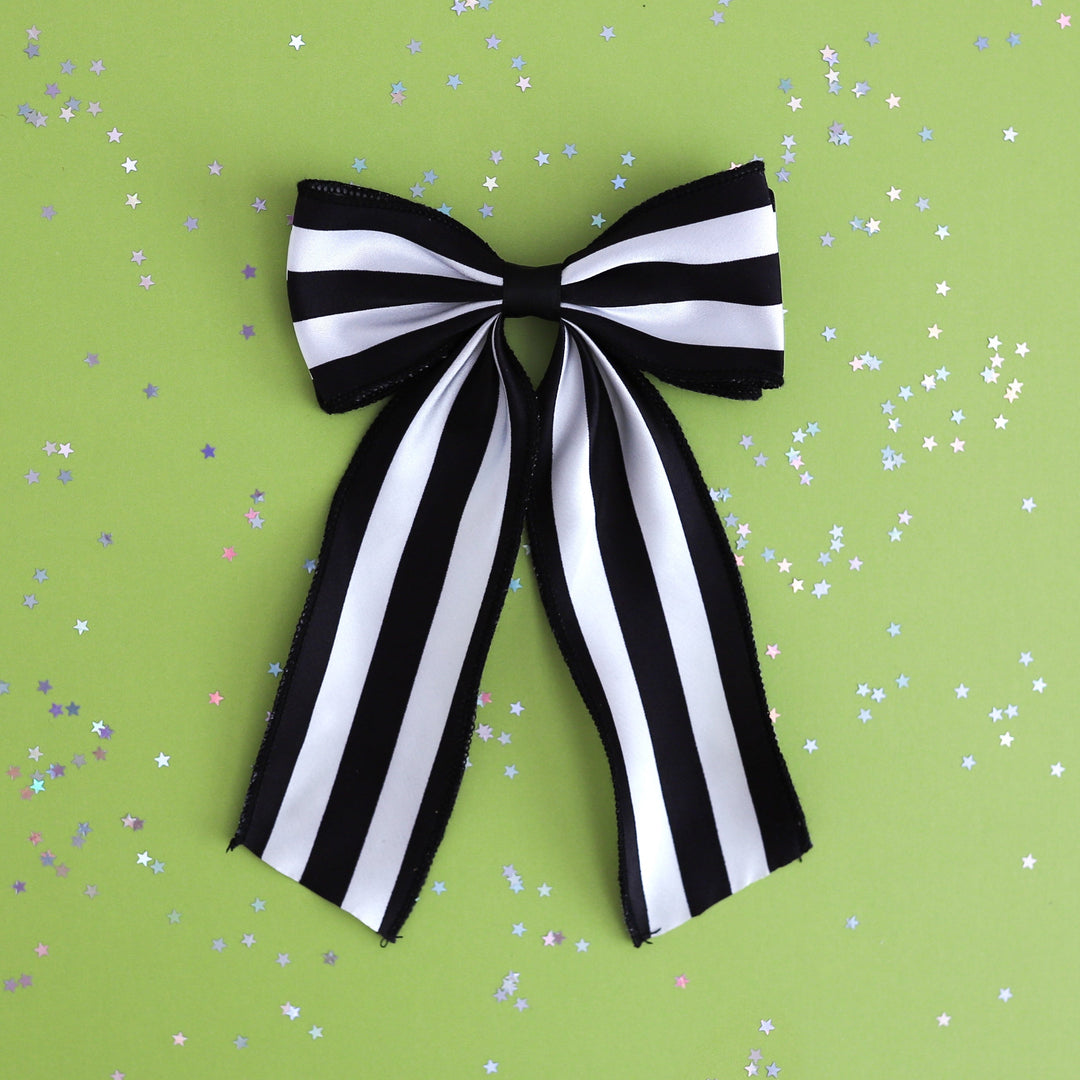 girls wide black and white striped oversized ribbon hair bow on clip photographed on green background with star confetti