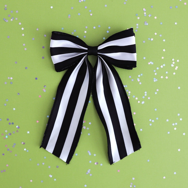 girls wide black and white striped oversized ribbon hair bow on clip photographed on green background with star confetti