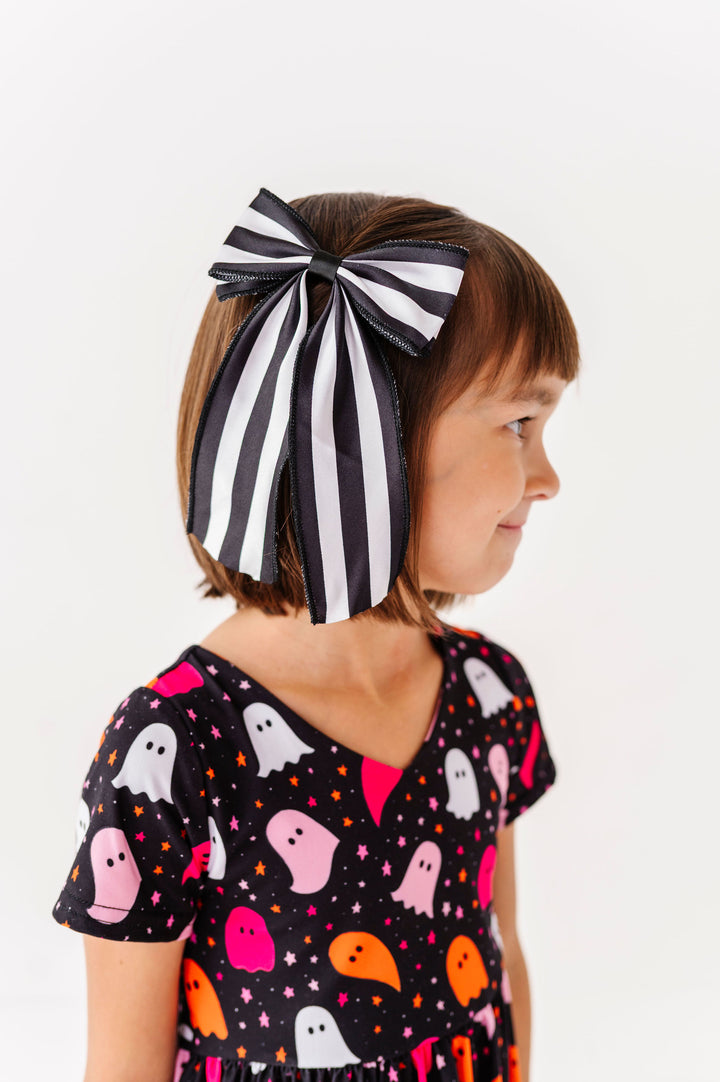 girl wearing black and white striped big hair bow with halloween dress