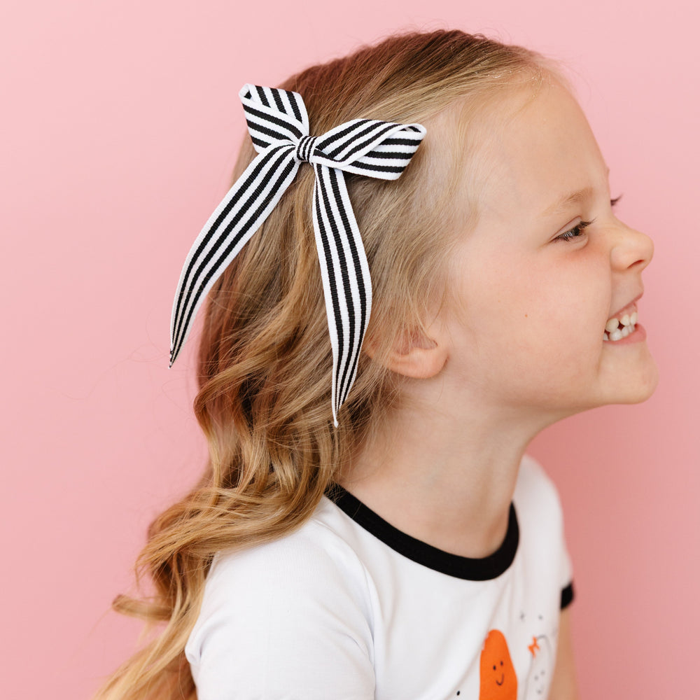 little girl in black and white striped ribbon bow on clip and matching ghost top for Halloween