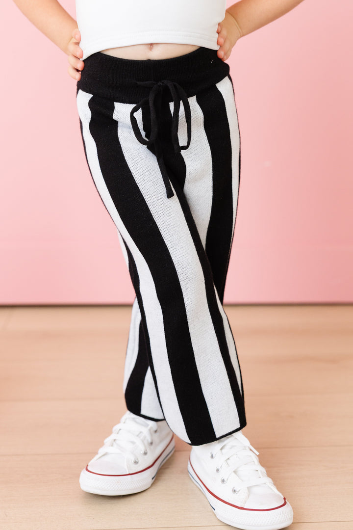 closeup of little girl in Halloween black and white striped cotton knit leggings with drawstring