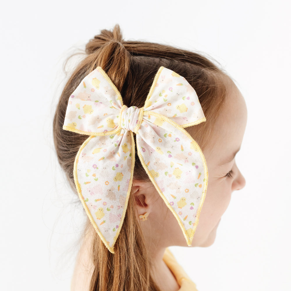 girl with bow that has easter bunnies and chicks and flowers with yellow trim